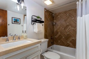 A bathroom with a double sink, toilet, bathtub, and shower.