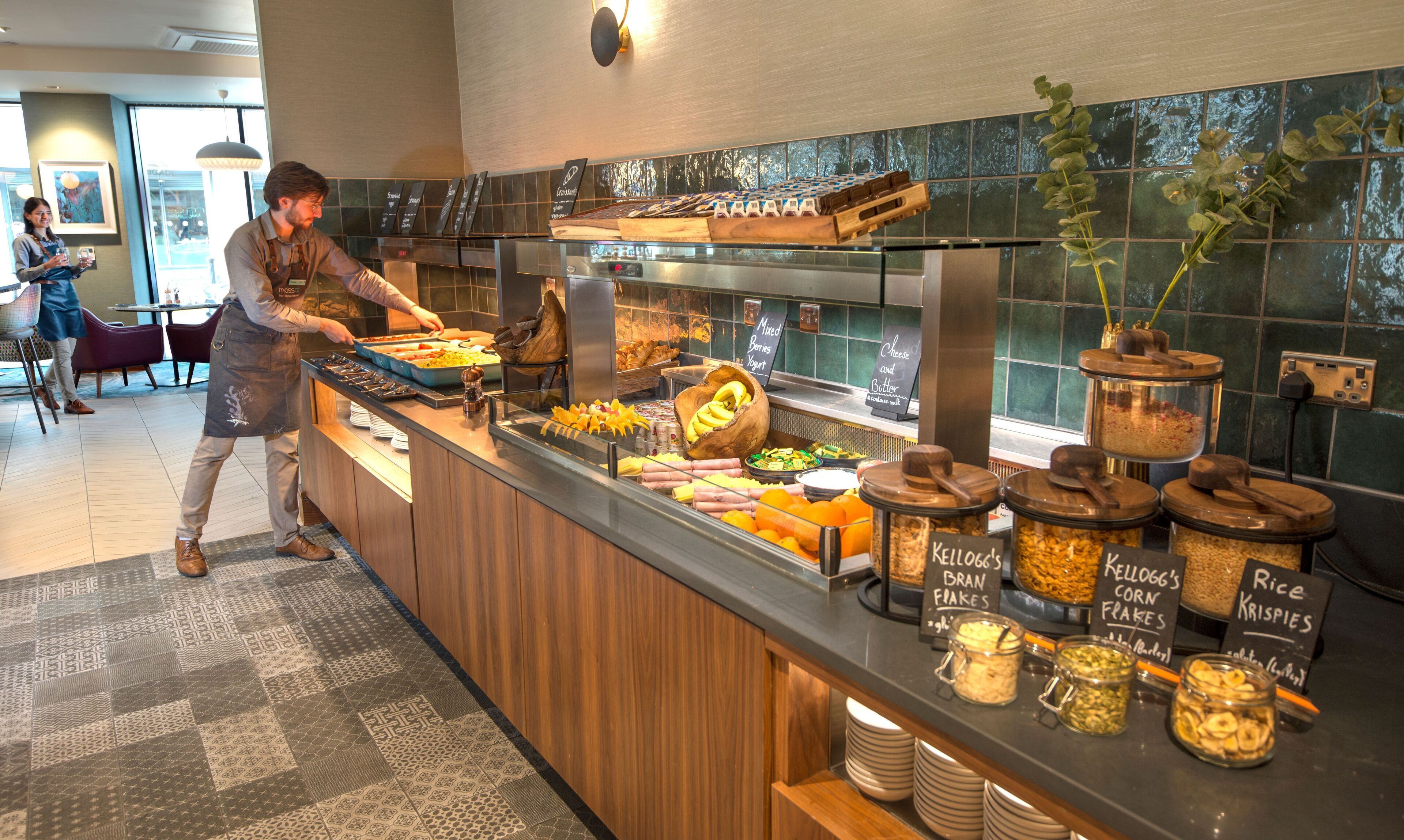 A buffet counter with various food items and a person serving.