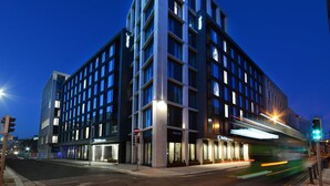 Un hotel moderno con ubicación en esquina, varios pisos y ventanas iluminadas.