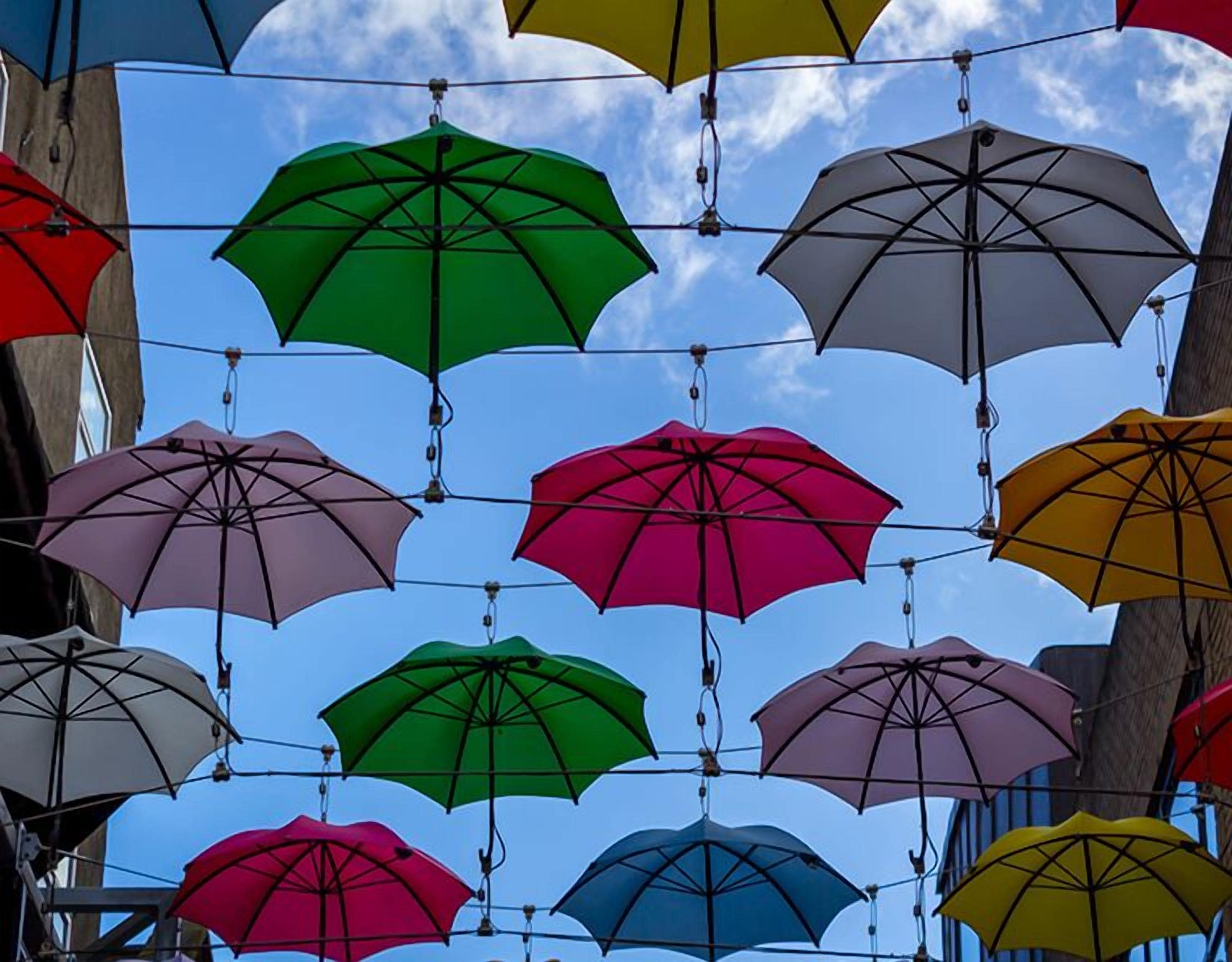 Diversi ombrelli sospesi nell'aria sotto un cielo sereno.