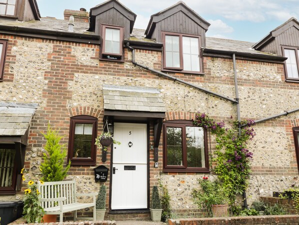 A two-story brick house with a white front door, a mailbox, and a bench outside. - Blueberry Cottage (Dorchester)
