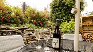 A table with a bottle of wine, two wine glasses, and a magazine. - Blueberry Cottage (Dorchester)