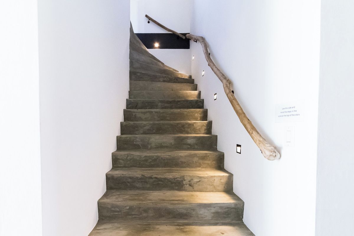 A staircase with a wooden handrail and a wall-mounted light fixture.