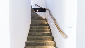 Una escalera con barandilla de madera y un aplique en la pared.