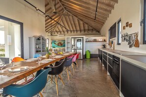 Una cocina moderna con techo de madera, un comedor con sillas de colores y vistas al exterior.