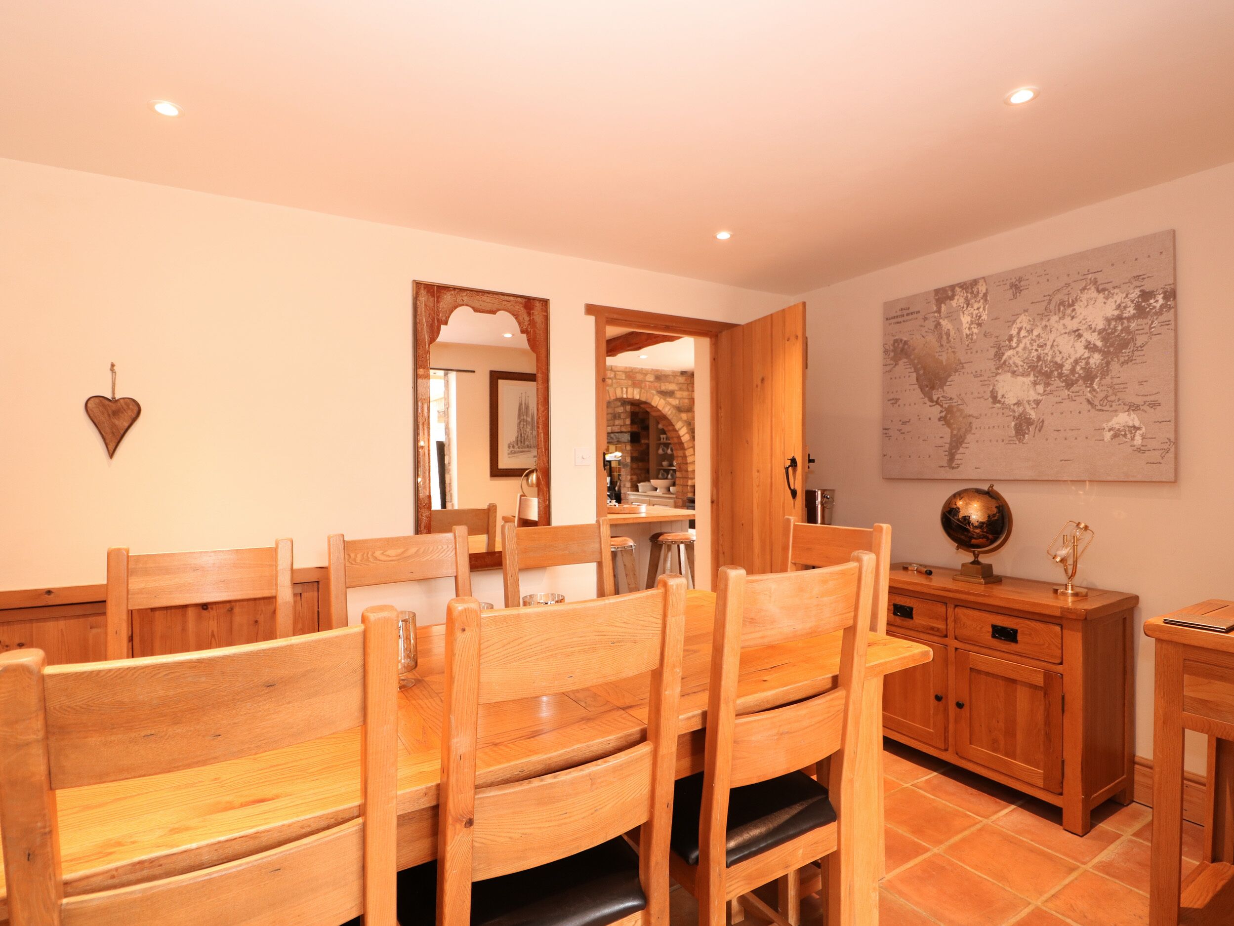 A dining area with wooden chairs and a table, a wooden cabinet with drawers, a globe, and a world map on the wall.