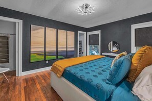 Une chambre à coucher avec un lit, une armoire, un miroir et un tableau accroché au mur.