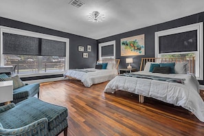 Un dormitorio con dos camas, un sofá, una silla y ventanas amplias.