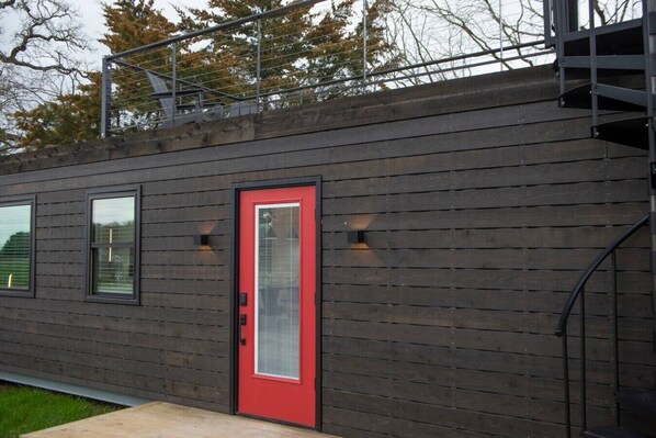 A modern building with a red door, large windows, and a staircase.