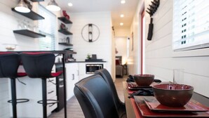 Cozinha moderna com área de jantar, incluindo banquetas de bar e uma mesa posta para dois.