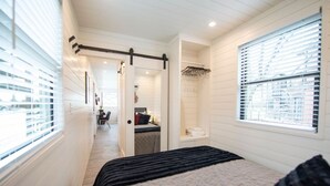 Quarto com cama, closet espaçoso, banheiro e área de trabalho.