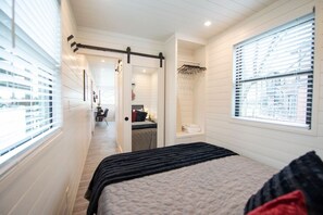 A bedroom with a bed, a walk-in closet, a bathroom, and a desk area.