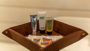 A brown leather toiletry bag with three tubes of body lotion and a bar of soap. - Deer Creek Tiny Container Home-12 Min to Magnolia (Waco)