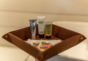 A brown leather toiletry bag with three tubes of body lotion and a bar of soap.