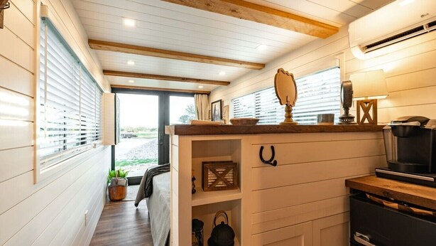 A compact kitchen with wooden cabinets, a coffee maker, and a view through the window.