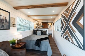 A cozy room with a bed, a desk, and a large abstract wall art piece.