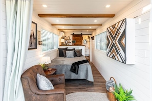 A cozy room with a bed, a brown leather chair, a small table, and a decorative wall piece.