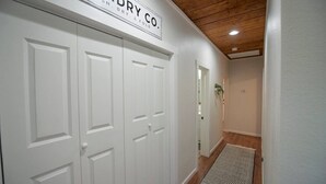 Un pasillo con puertas blancas, un letrero que dice 'WASH DRY & FOLD', piso de madera y una alfombra estampada.