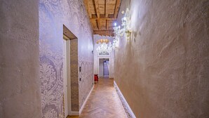 A hallway with patterned wallpaper, wooden flooring, and a chandelier. - Corte Rubbi 5 Deluxe Studio-Apartment (Venice)