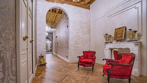 A hallway with wooden flooring, white walls, and two red chairs. - Corte Rubbi 5 Deluxe Studio-Apartment (Venice)