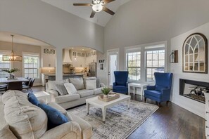 Un salon spacieux comprenant un canapé, des fauteuils, une table basse et une cheminée.