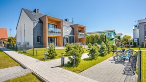 Ein modernes Hotel mit zweistöckiger Bauweise, Außenbereich zum Sitzen und einem Fahrradstellplatz.