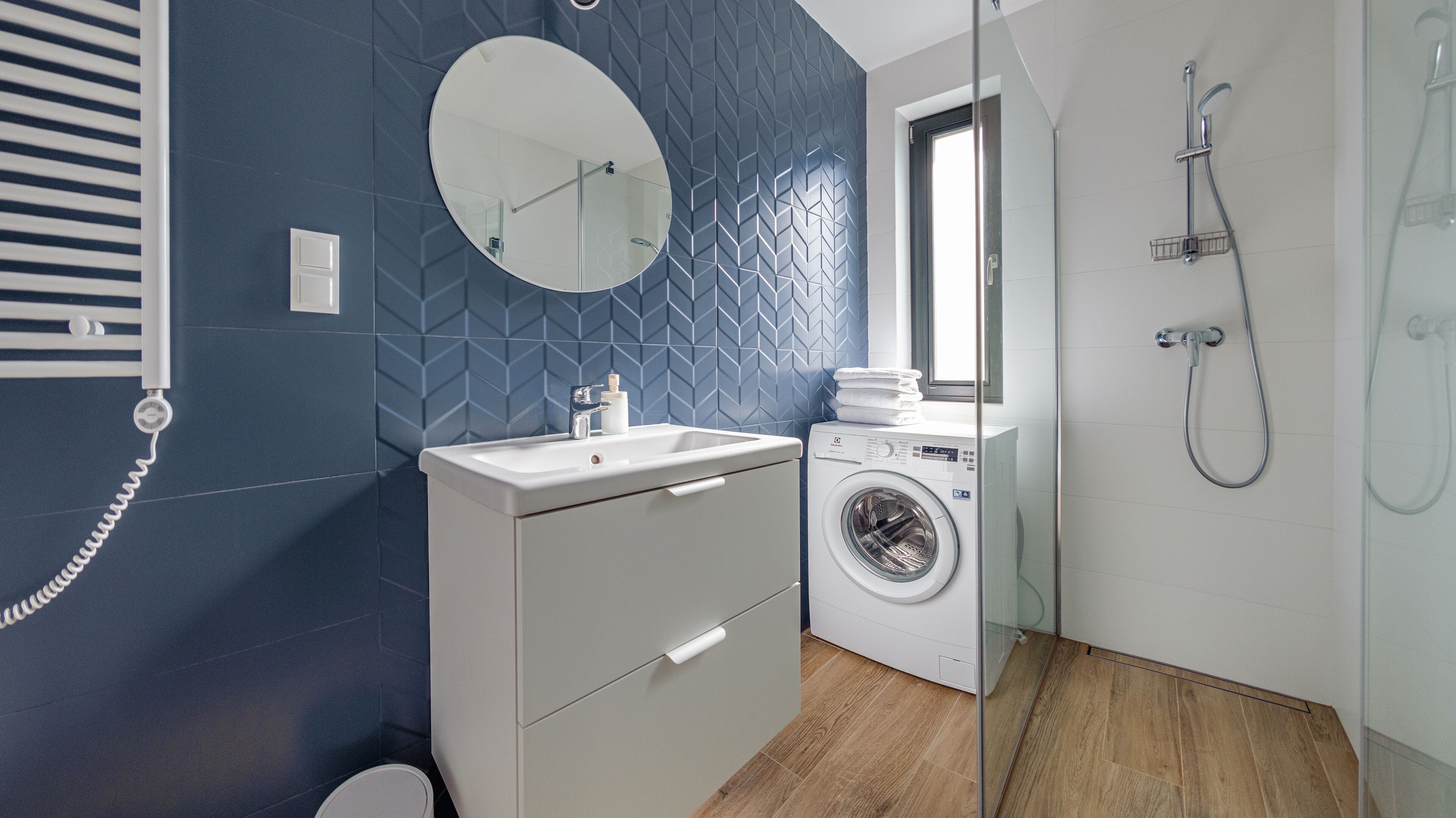 Un baño moderno con lavadora, lavabo y ducha.