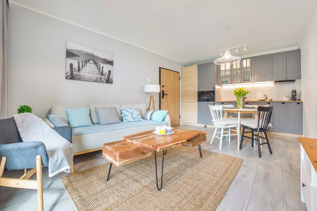 A modern living room with a sofa, coffee table, and dining area.
