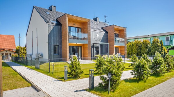 A modern building with a flat roof, large windows, and a wooden facade. - Apartamenty Sun & Snow Nautikka Resort (Krynica Morska)