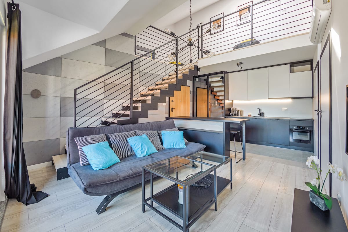 A modern living room with a sofa, coffee table, and a staircase leading to an upper level.