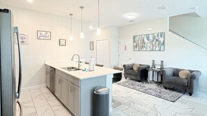 Una cocina moderna con suelo de mármol, una isla central e iluminación colgante.