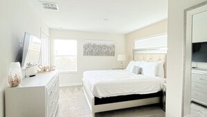 Un dormitorio con cama, cómoda y un espejo grande.