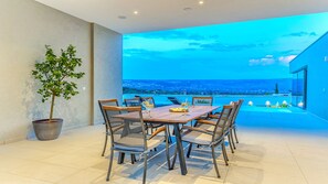 Un comedor con mesa y sillas, una planta en maceta y vistas al mar.