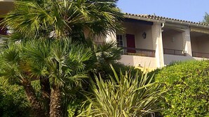 Un bâtiment à la façade blanche, aux volets rouges et au toit recouvert de tuiles.