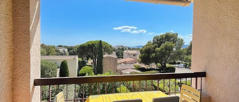 A covered outdoor patio with a table and chairs, a view of a town, and a clear sky.