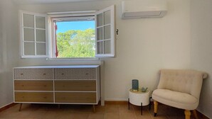Une pièce avec une fenêtre, une armoire blanche, une chaise et une petite table.