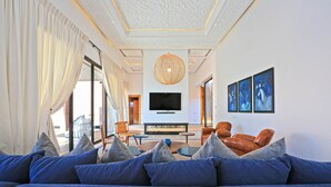 A modern living room with a large sofa, a television, and artwork on the wall. - Impeccable 5-bed Villa in Marrakech (Marrakech)