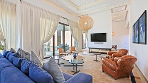 A modern living room with a sofa, armchairs, a TV, and a large window with curtains. - Impeccable 5-bed Villa in Marrakech (Marrakech)
