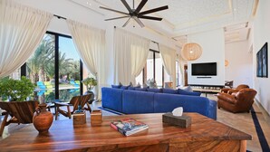 A modern living room with a blue sofa, wooden coffee table, and a ceiling fan. - Impeccable 5-bed Villa in Marrakech (Marrakech)