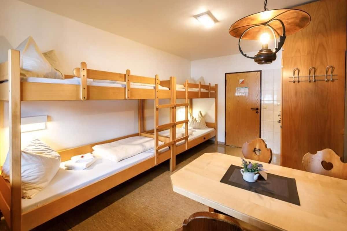 Ein Schlafzimmer mit Etagenbetten, einem Holztisch und einer Hängeleuchte.
