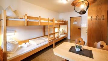 Dormitorio con literas, una mesa de madera y una lámpara colgante.