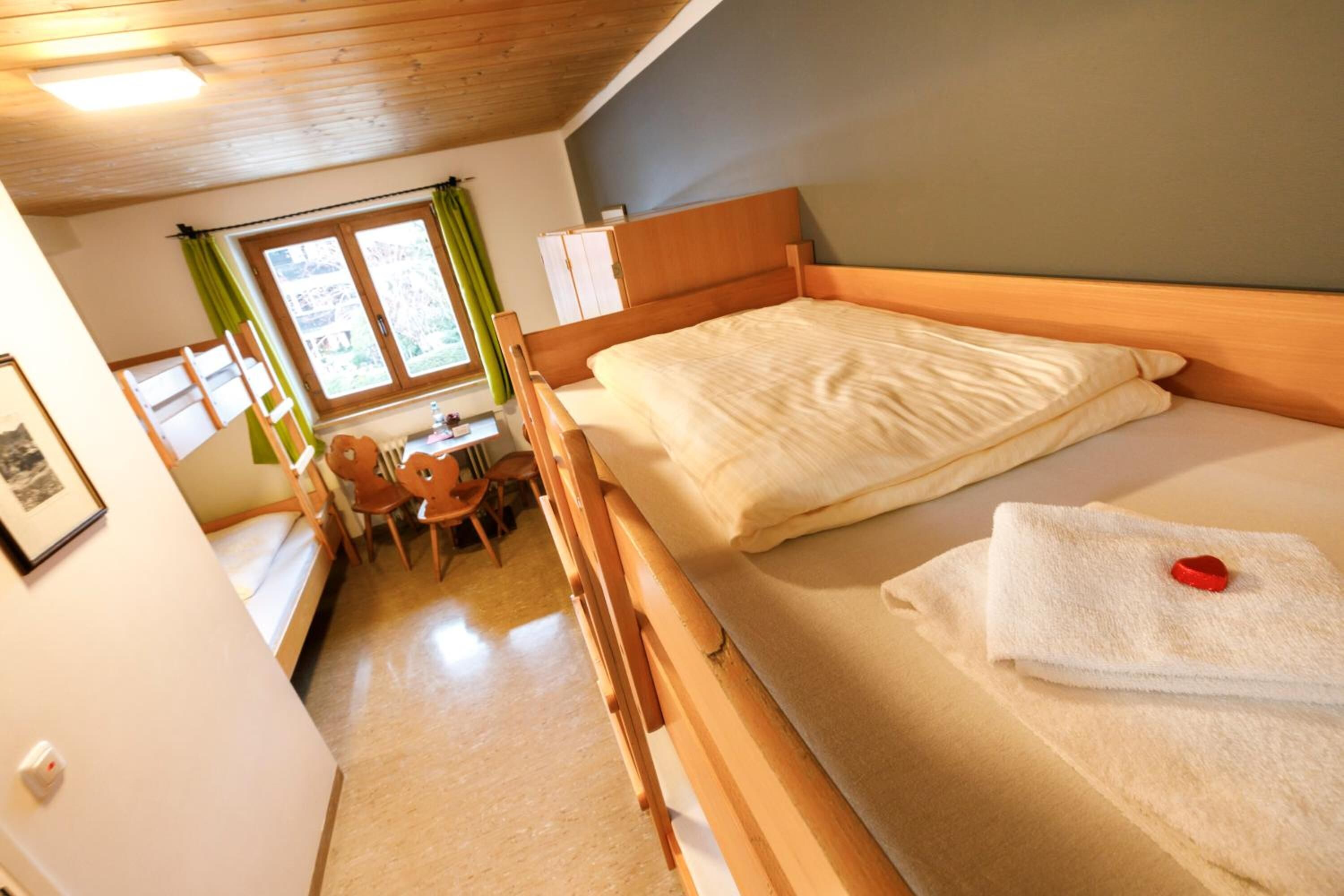 Um quarto aconchegante com uma cama de madeira, uma escrivaninha pequena e uma cadeira.