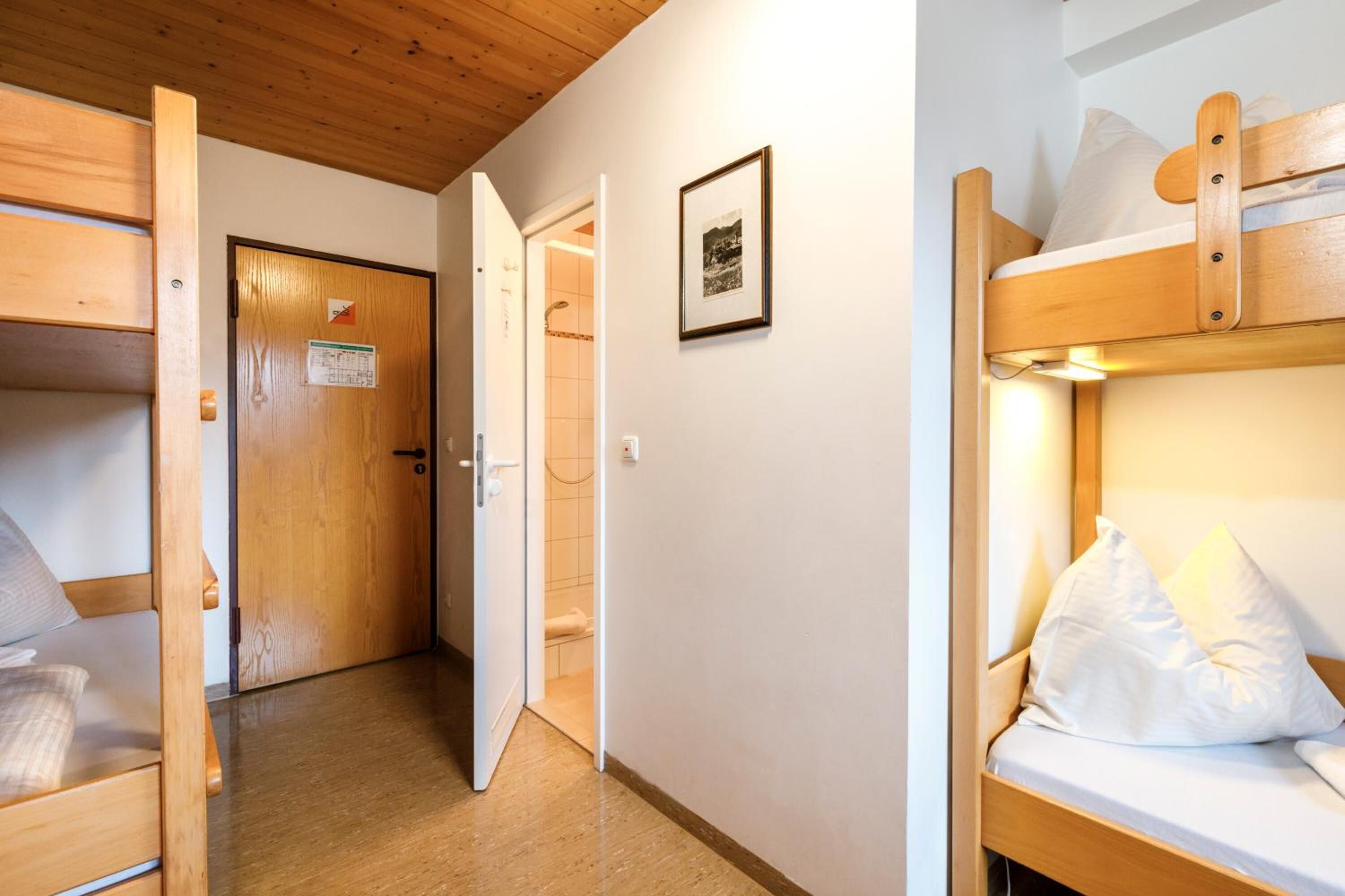 A room with a bunk bed, a wooden door, and a framed picture on the wall.