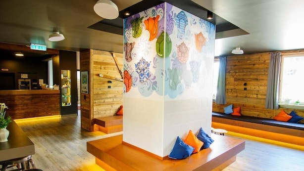 A modern interior with a central seating area, wooden walls, and a colorful wall decoration.
