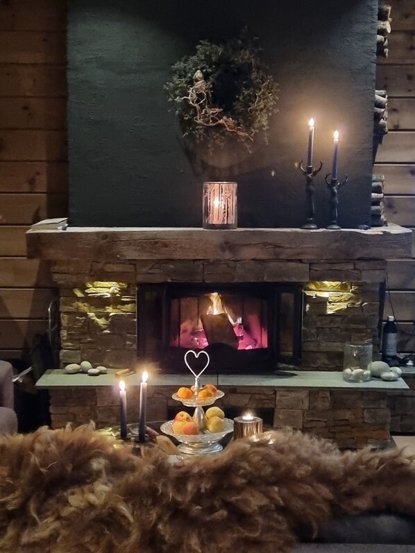 Una chimenea de piedra con una planta encima, un candelabro y una bandeja de pasteles.