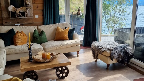 A cozy cabin-style room with a large window offering a view of a lake and trees.