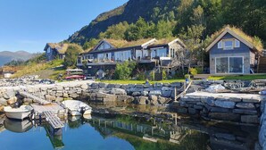 A lakeside property with a dock, stone walls, and modern houses with large windows.