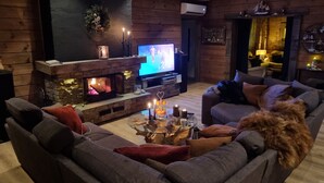A cozy living room with a stone fireplace, a television, and a comfortable seating area.