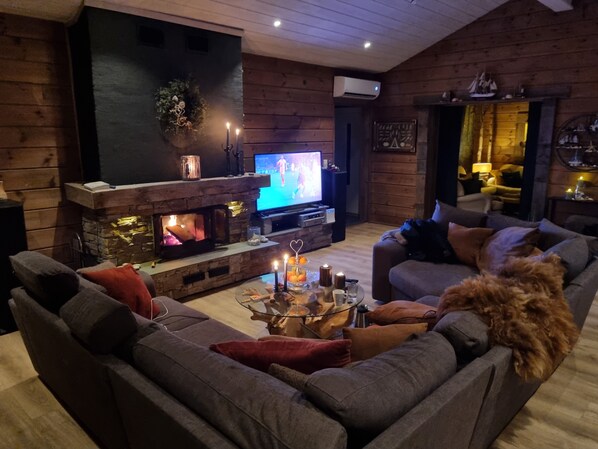 Uma sala de estar aconchegante com lareira de pedra, televisão e um espaço de estar confortável.