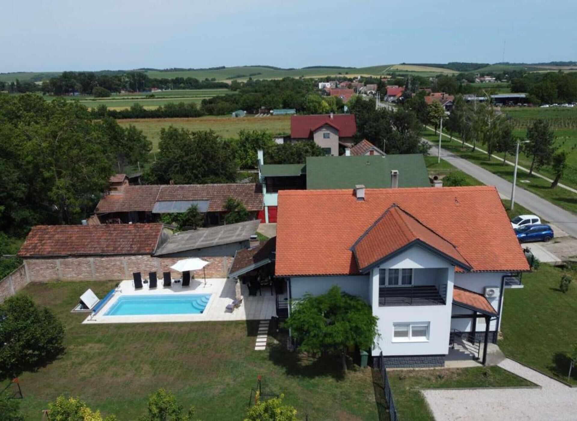 Zona residenziale con case, una piscina e un paesaggio verde.